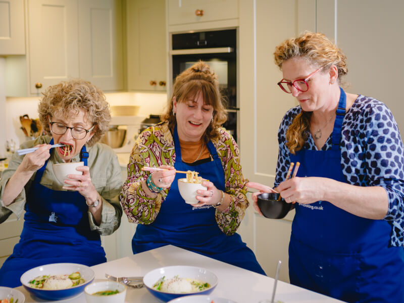 Three women sampling what they've made at a Thai cooking class